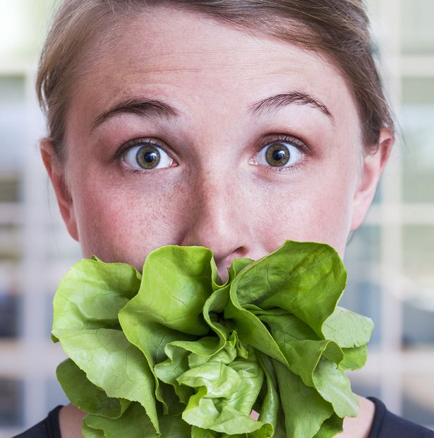 Young woman with mouth stuffed with salad lettuce Everything you know about diets is wrong   and you CAN eat food you think